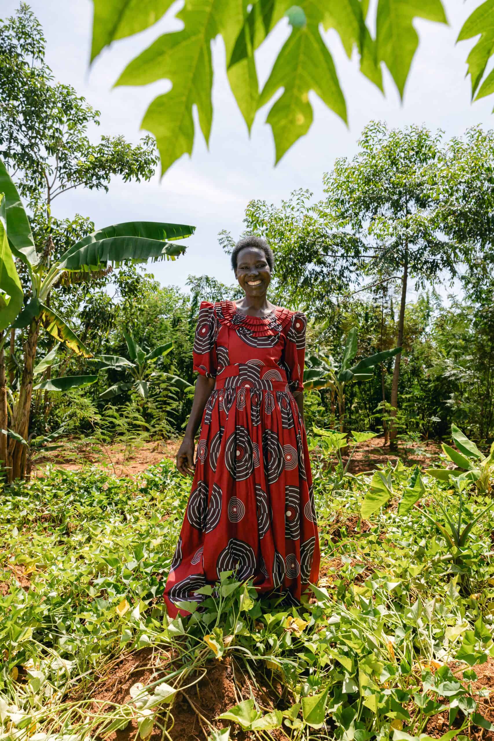 Smiling woman in vibrant dress standing amidst lush green plants supported by Trees®中国幸运体彩飞艇168网 for the Future