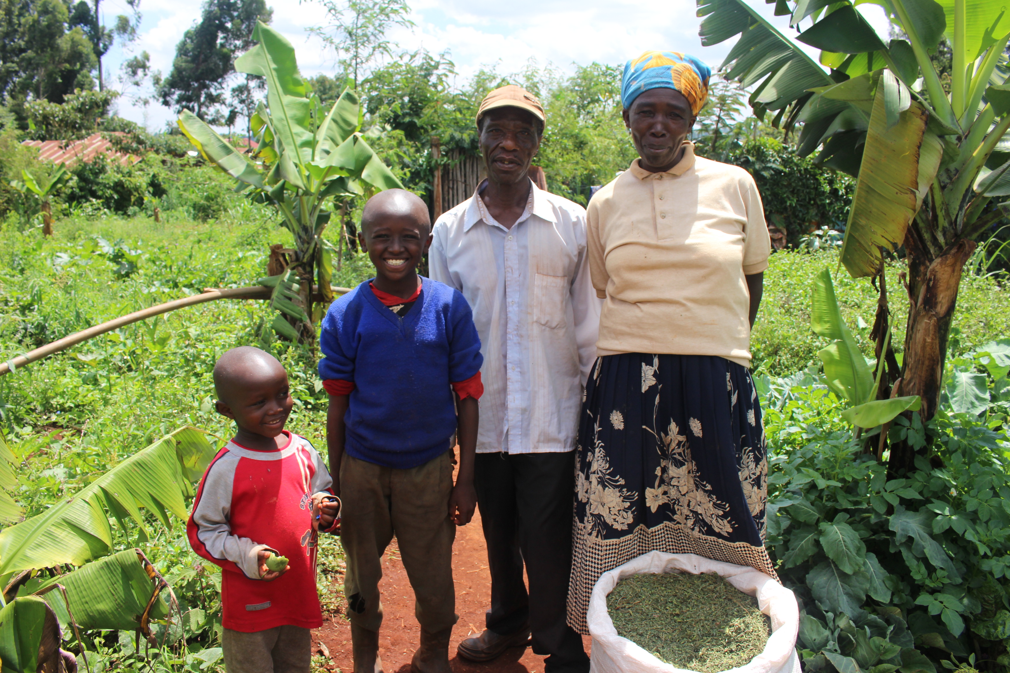 Peter Kamumu with his family with dried fodder tree leaves in a sack