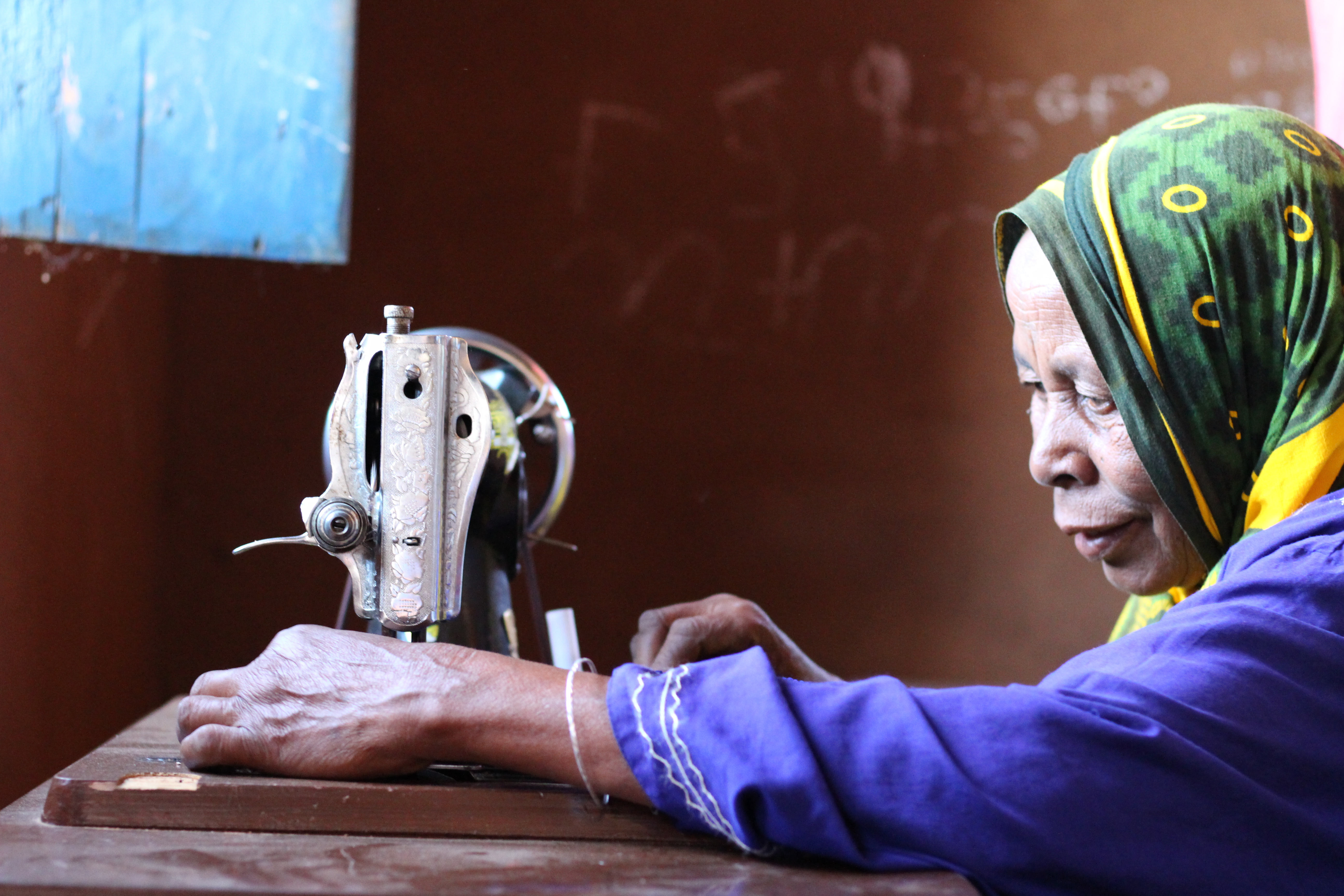 A woman from our Forest Garden program learning to sew
