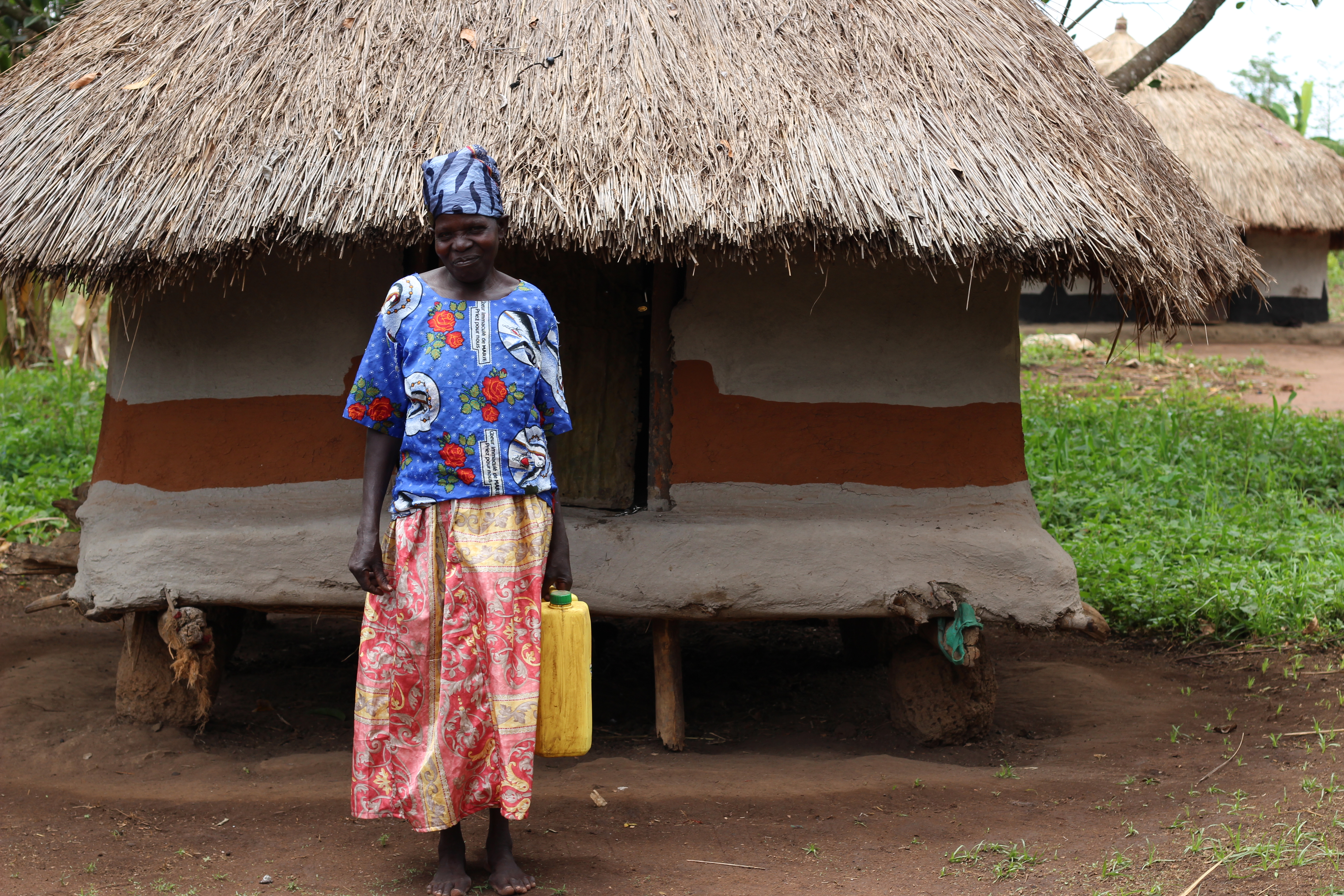 Ajok standing in front of her hut
